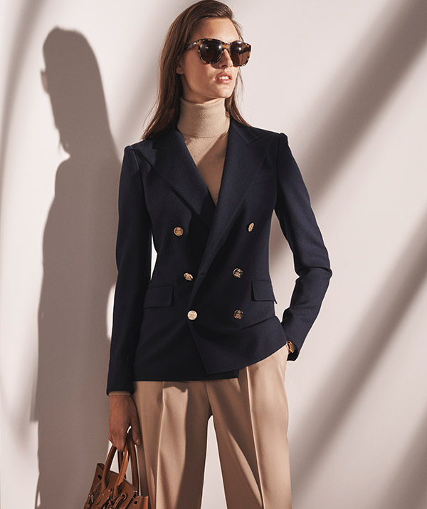 Woman wears navy blazer with gold-tone buttons