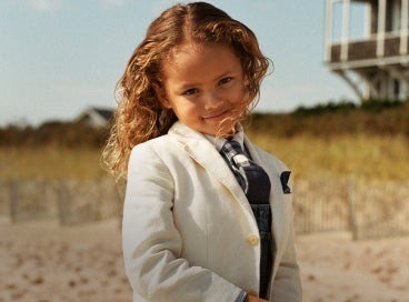Kid on beach wears white sport coat.