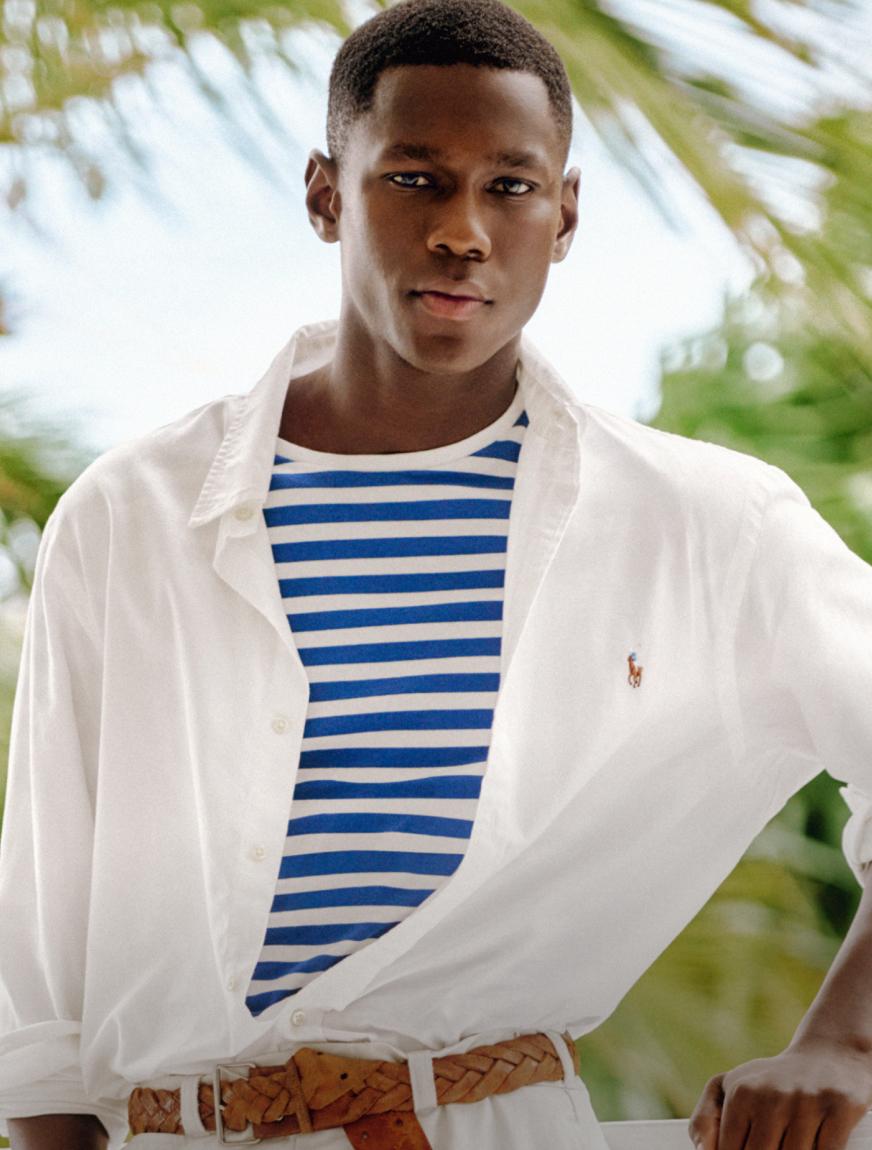 Man wears a white long-sleeve Polo shirt over a striped T-shirt.