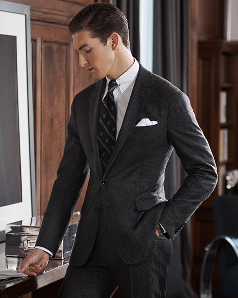 Man in black suit looks at newspaper