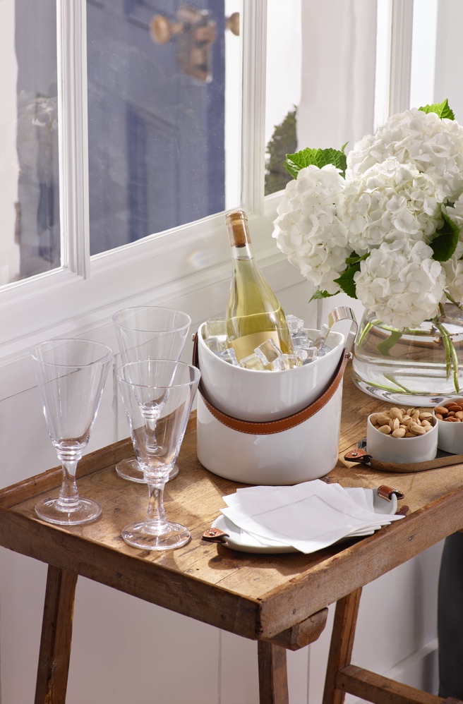 White wine bucket with leather trim on wooden side table.