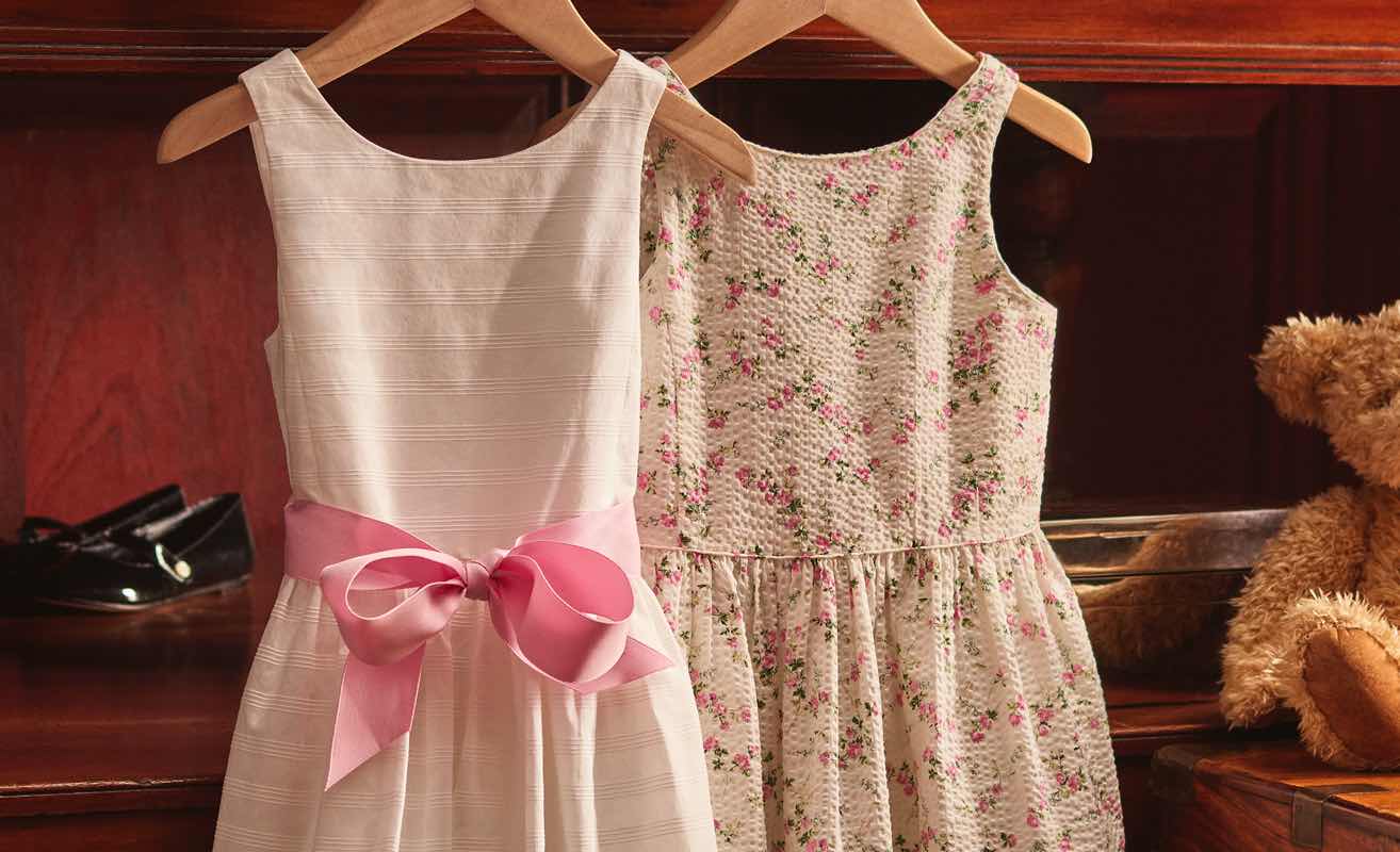 White and floral dresses on wooden hangers.