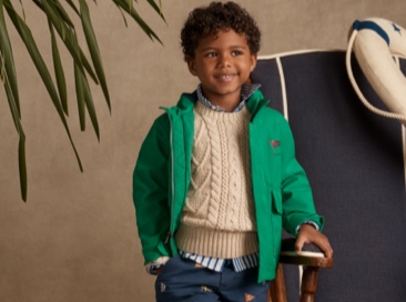Boy wears green jacket over cream sweater.