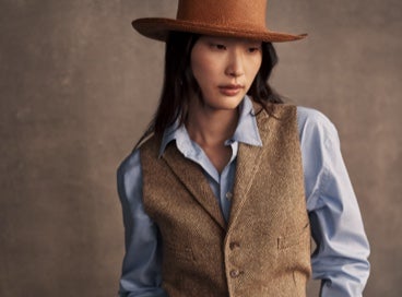 Woman wears herringbone suit vest over button-down shirt.