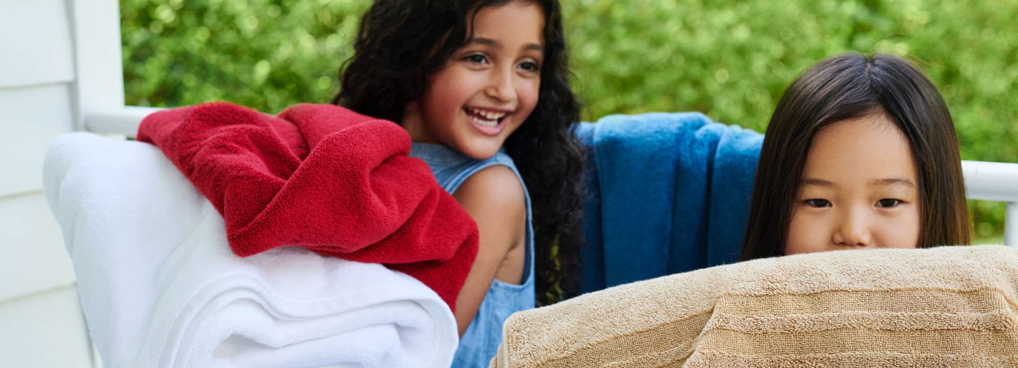 Girls hold bath towels on porch.