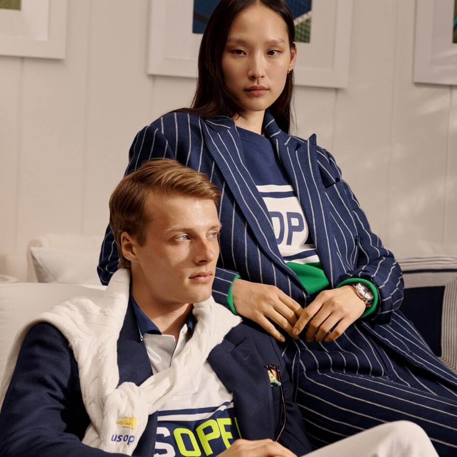 Woman wears navy pinstripe suit; man wears blazer over US Open shirt.