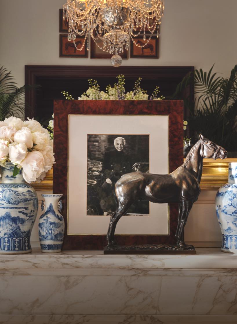 Framed picture of Ralph, flowers, and other home items on mantle.