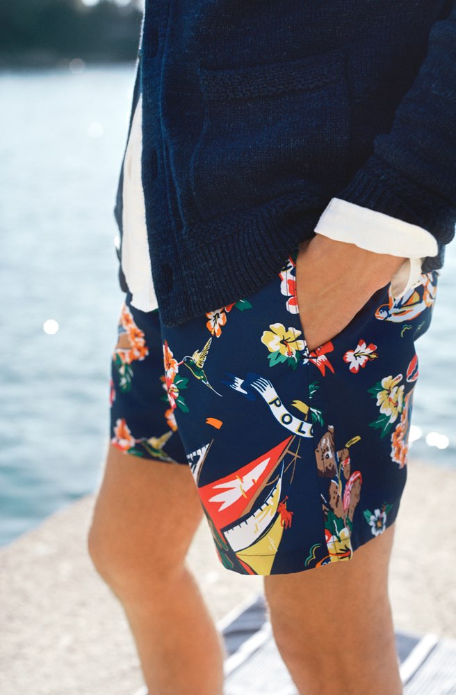 Man in navy swim trunks with colorful floral & sailboat motifs
