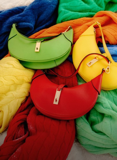 Brightly colored leather handbags on brightly colored cable-knit sweaters.