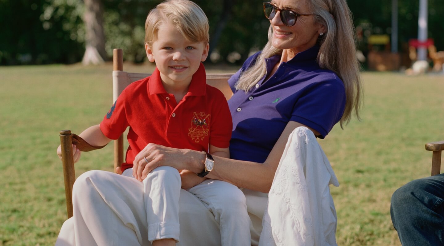 Boy in red Polo shirt sits on woman's lap.