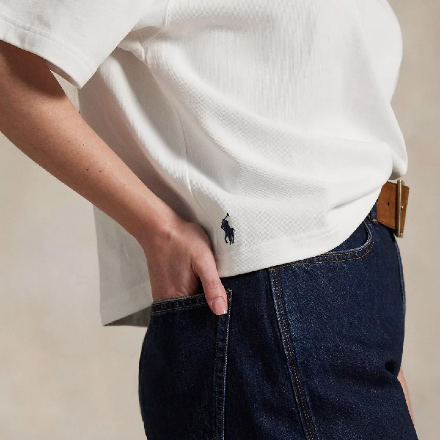 Woman wears cropped white tee and dark-wash jeans.