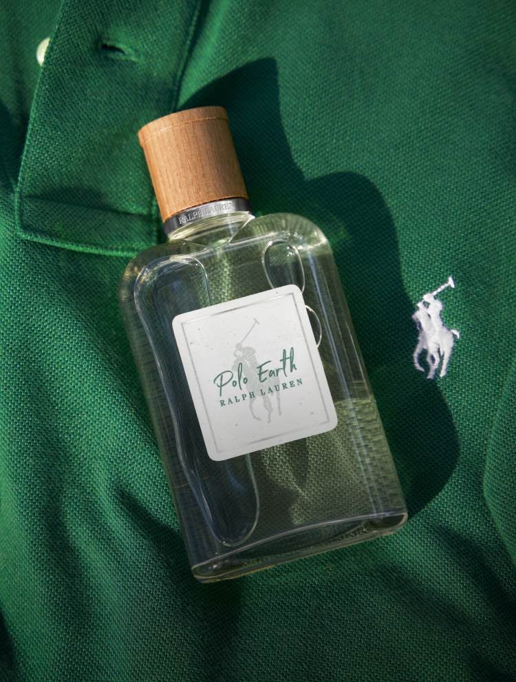 Clear fragrance bottle with wood cap on green Polo shirt.