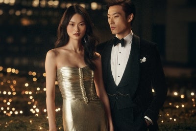 Woman and man wear gold satin dress and black tuxedo.