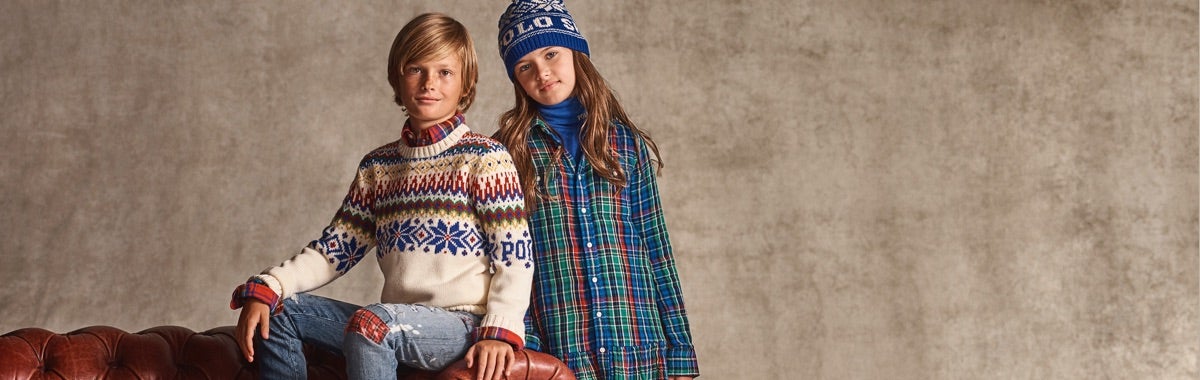 Boy wears colorful Fair Isle sweater; girl wears plaid shirtdress.