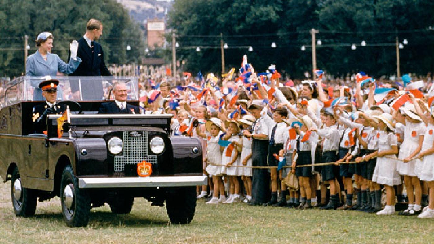 From the back of a Defender during a royal tour in 1954, Queen Elizabeth II and her husband, Prince Philip, wave to a crowd of children in New South Wales, Australia