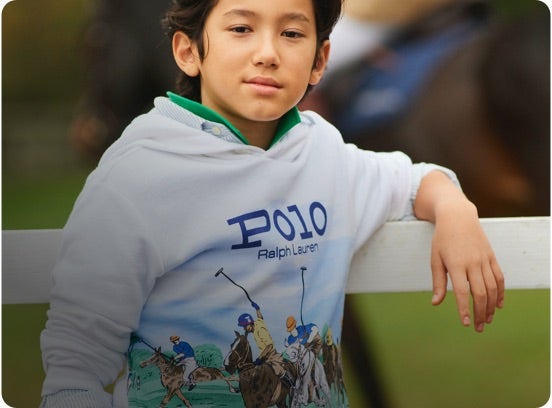 Boy in white hoodie with polo match print at front.