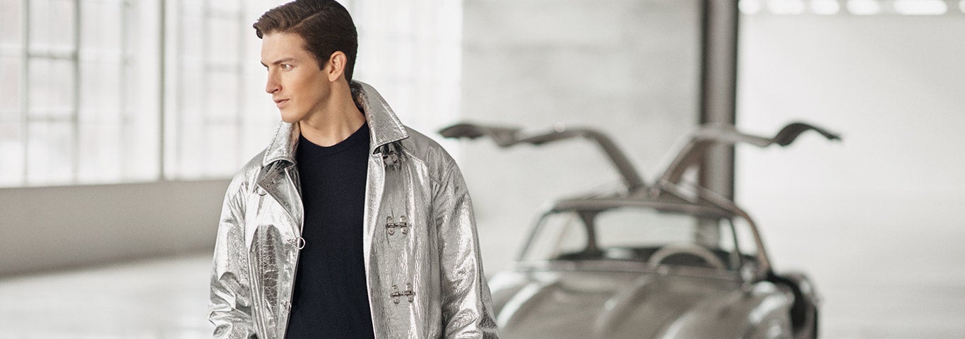 Man in metallic silver fireman's jacket standing next to silver car