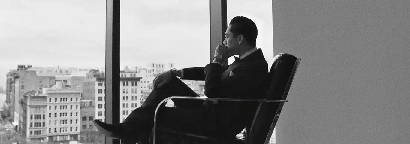 Man in suit sitting in chair looking out of window