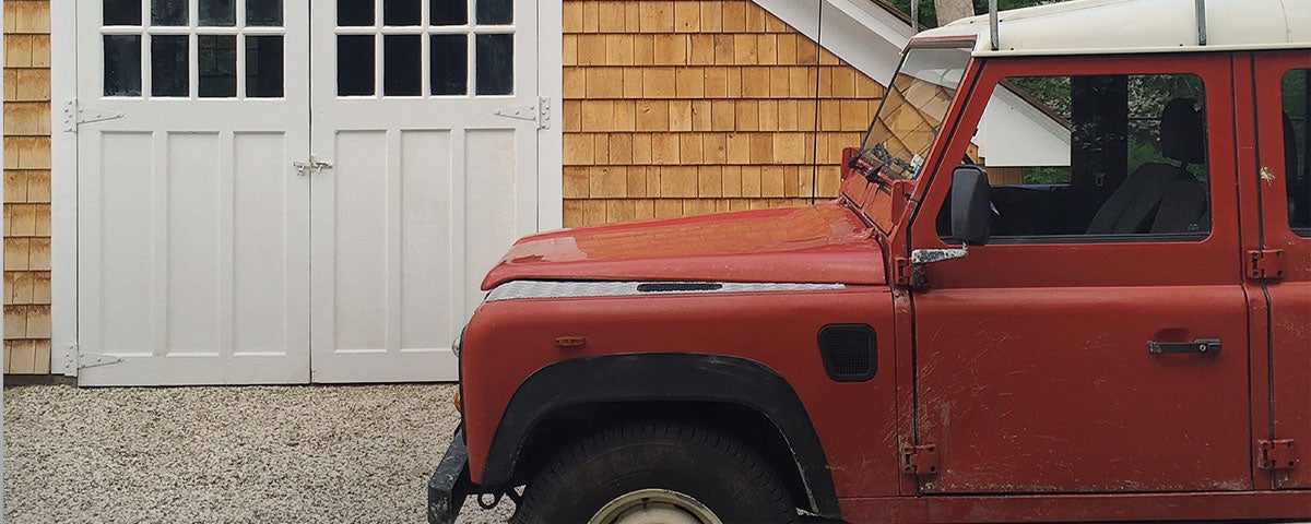 Red jeep parked in front of wood-paneled cottage