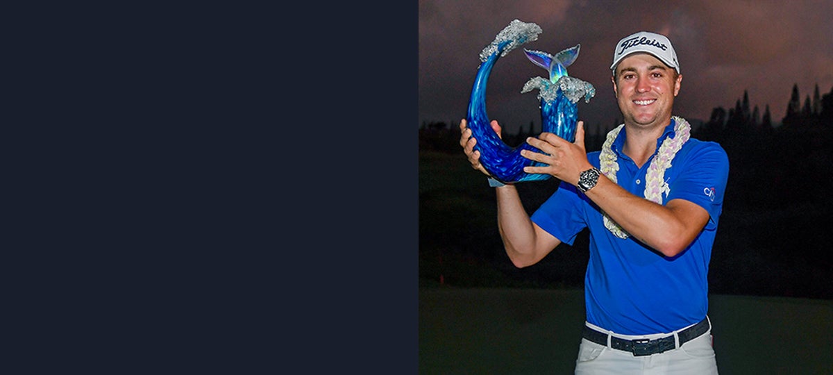 Justin Thomas in royal blue Polo shirt holding up Tournament of Champions trophy