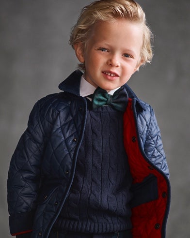 Boy wears navy quilted coat over navy cable-knit sweater