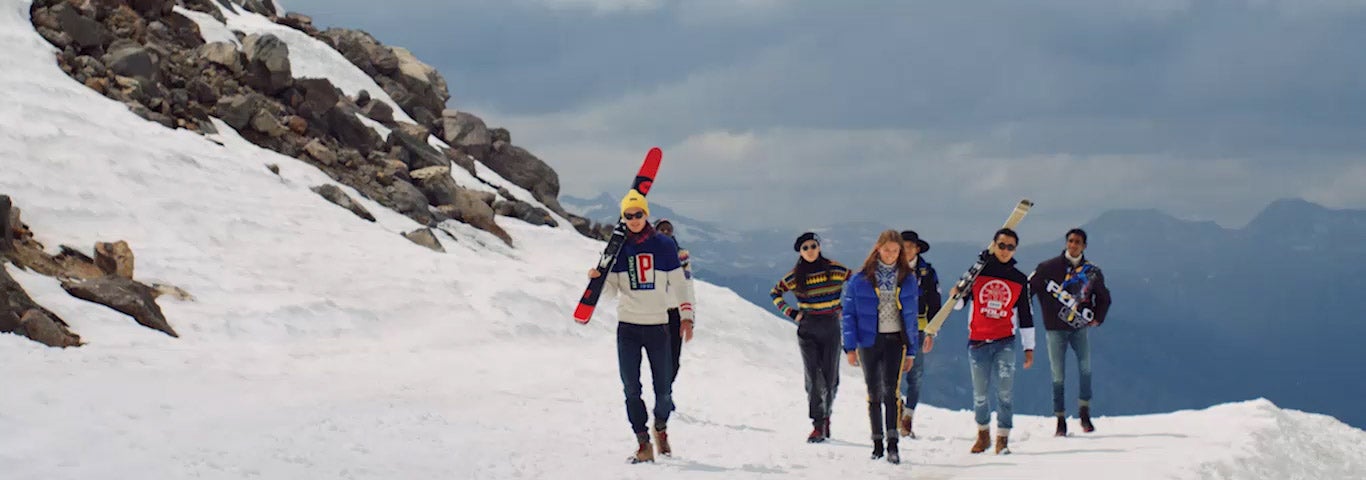 Men in color-blocked Polo outerwear carrying skis on mountain