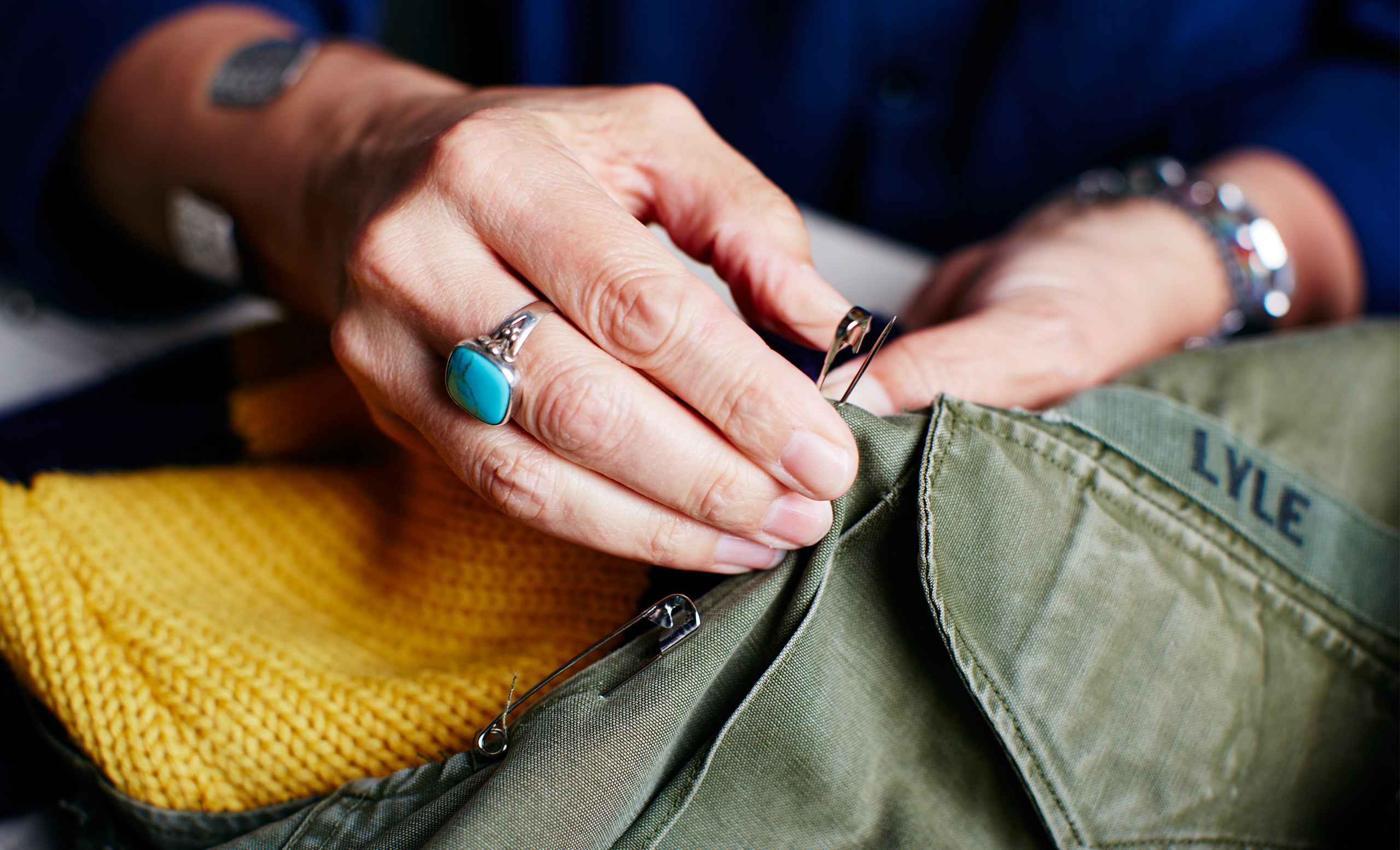 <strong>STEP 4: PINNING</strong> <br/>The individual pieces are pinned together to create a prototype. Signature patches and grosgrain are added.