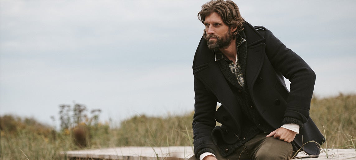Man in peacoat layered over cardigan & plaid shirt