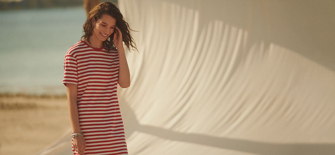 Woman on beach in red-and-white striped T-shirt dress