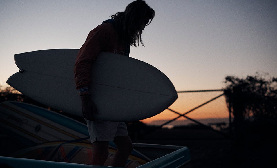 Silhouette photograph of surfer carrying surfboard.