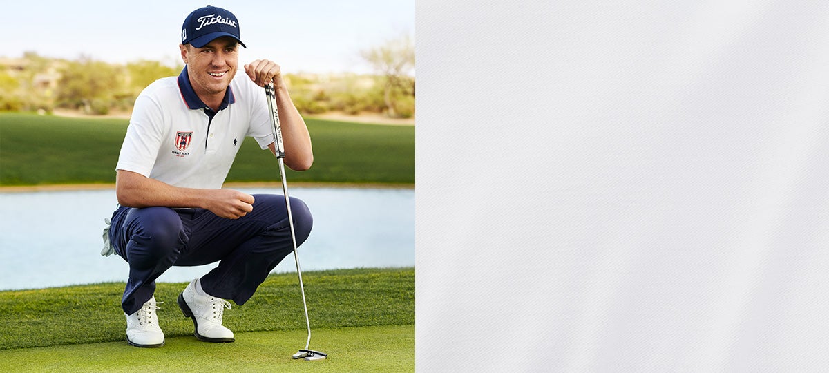 Justin Thomas crouching on green in white Polo shirt with navy collar