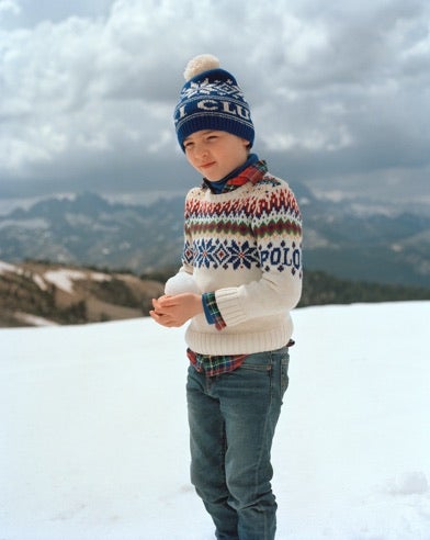 Boy in blue snowflake-patterned knit pom-pom hat