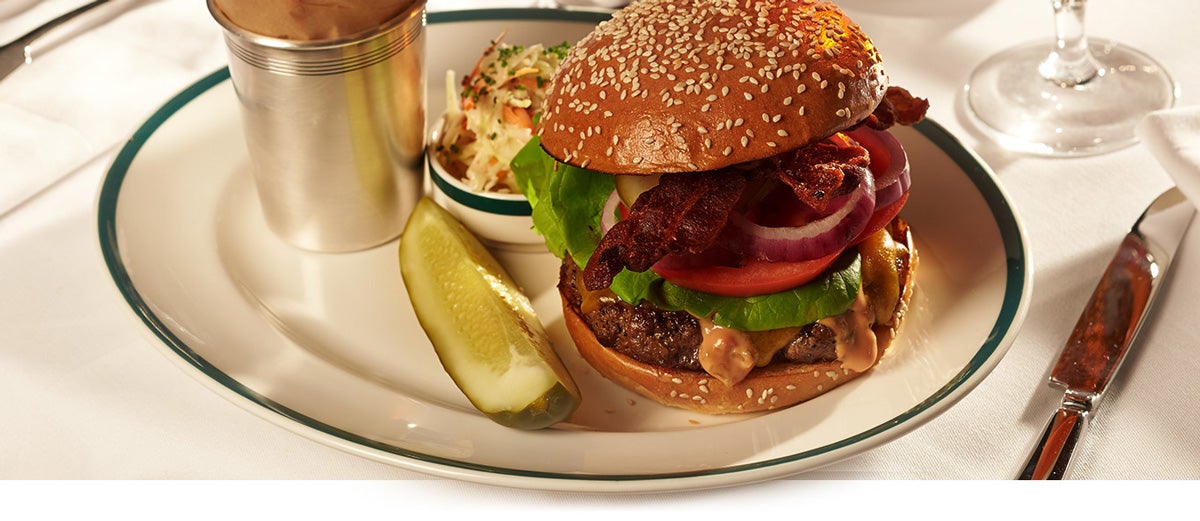 Burger, pickle & fries on ceramic plate with dark green trim