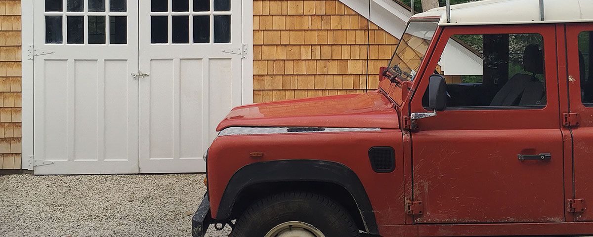 Red jeep parked in front of wood-paneled cottage
