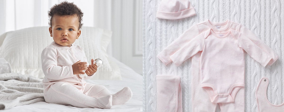 Baby girl wears pink one-piece; gift set of light pink outfits and accessories.