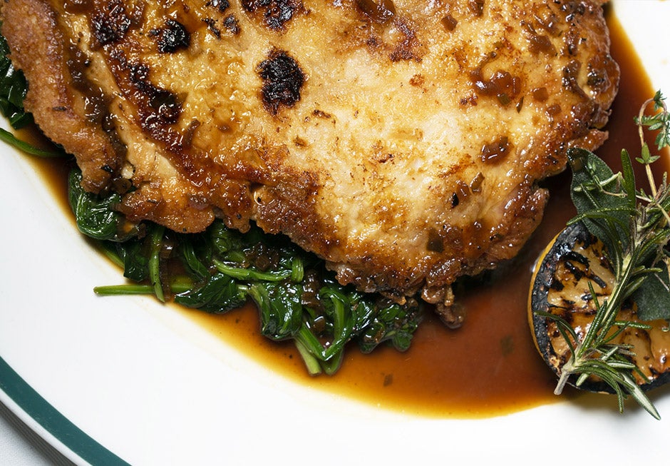 Close-up of plate with grilled chicken and grilled lemon.