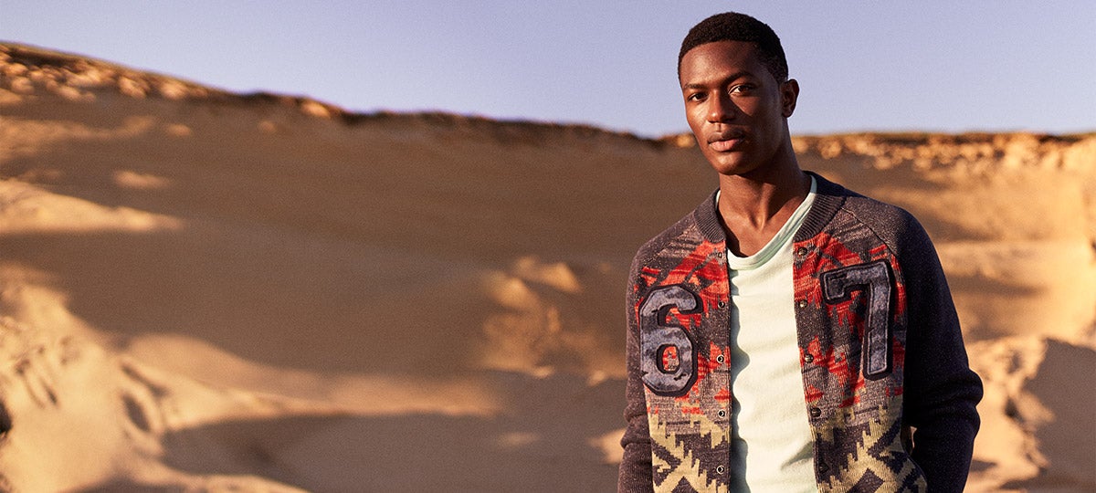 Man wears snap-front baseball sweater with blanket motif.