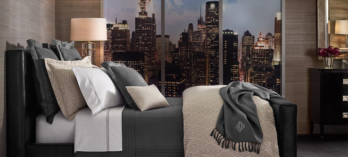 Neatly made bed with crisp sheeting in white and dark grey