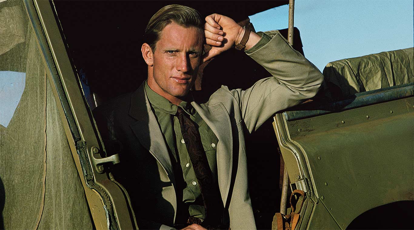 Man in go-everywhere suit and Safari watch poses in Land Rover