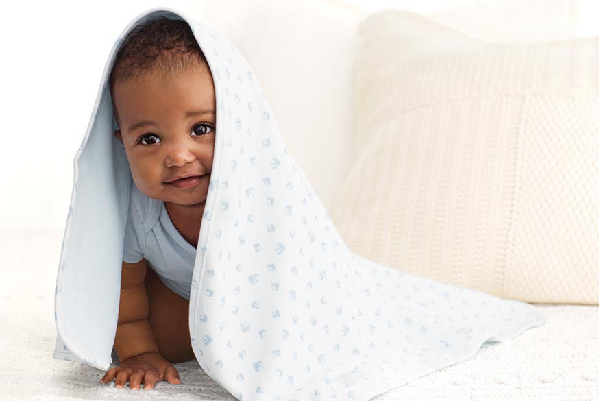 Baby Checklist Newborn Must Haves Ralph Lauren Baby In Blue Onesie Crawls Under Patterned Blanket