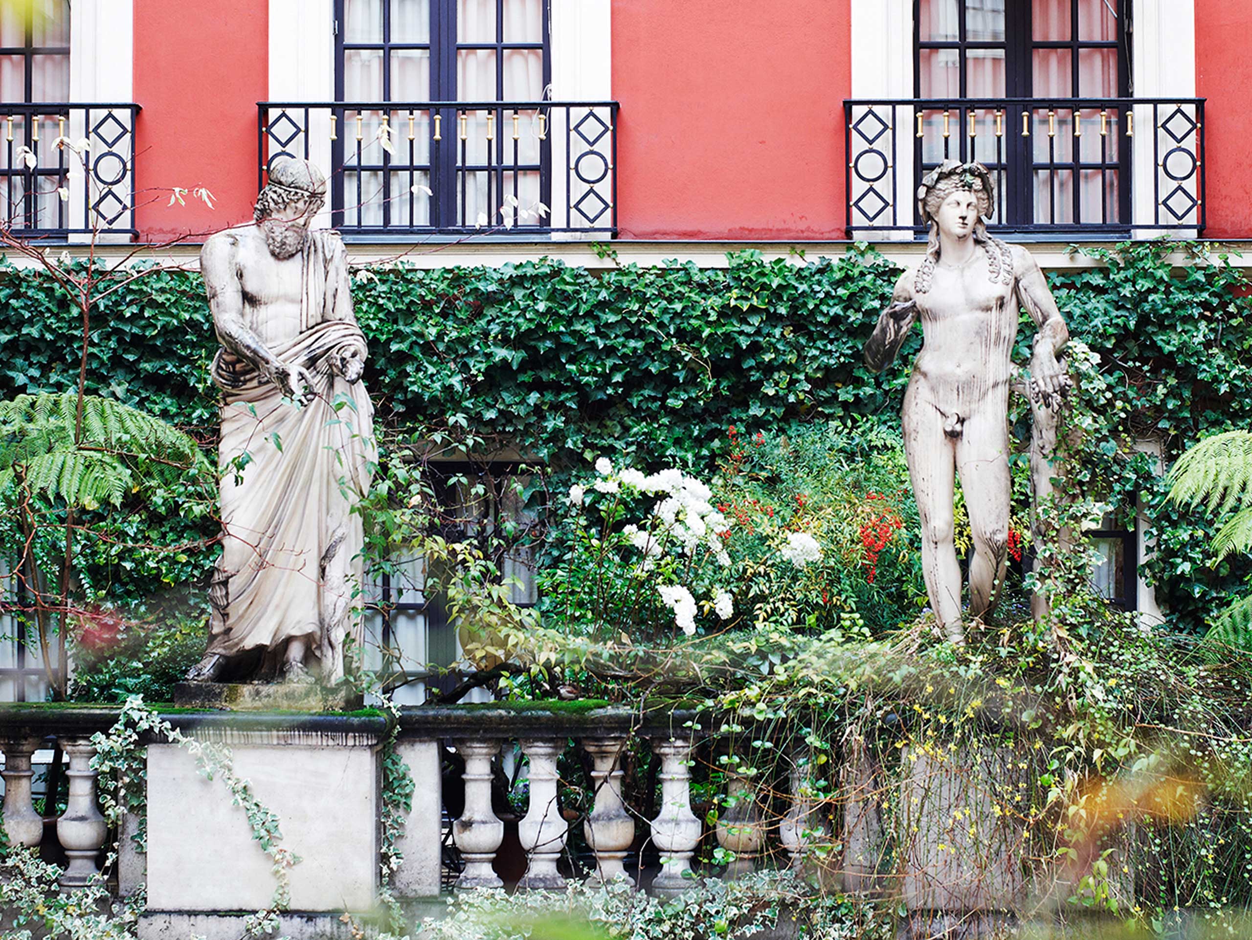 The interior courtyard of H<span>ô</span>tel Costes in Paris features sprawling ivy and large statues