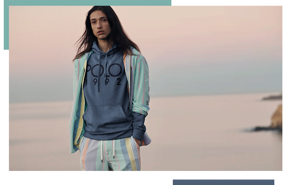 Model wears blue Polo hoodie and multicolored striped shorts.