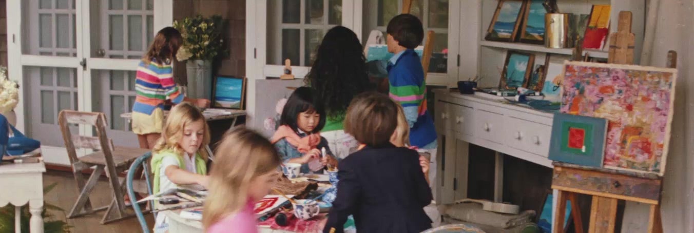 Kids in Polo styles sit at table making art.