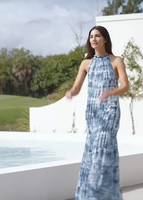 Woman wears halterneck tie-dye maxidress.