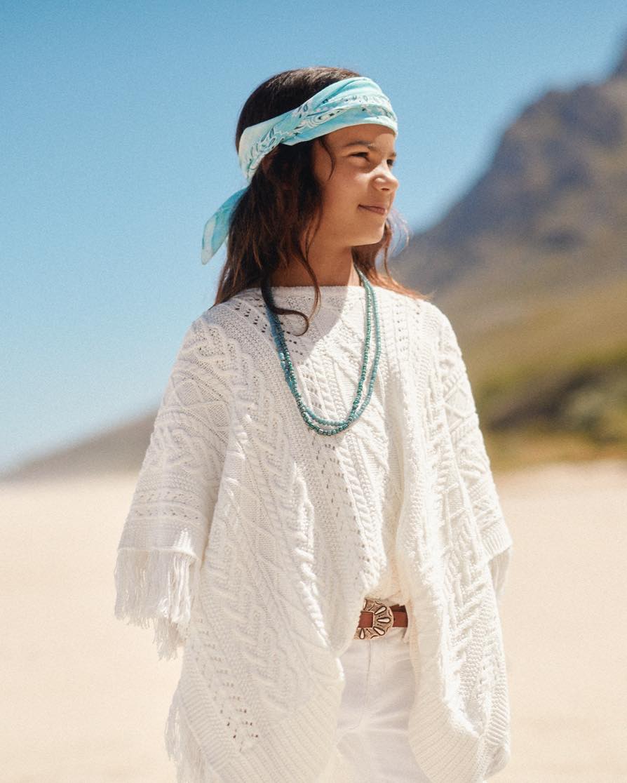 Girl in white fringe poncho & white pants