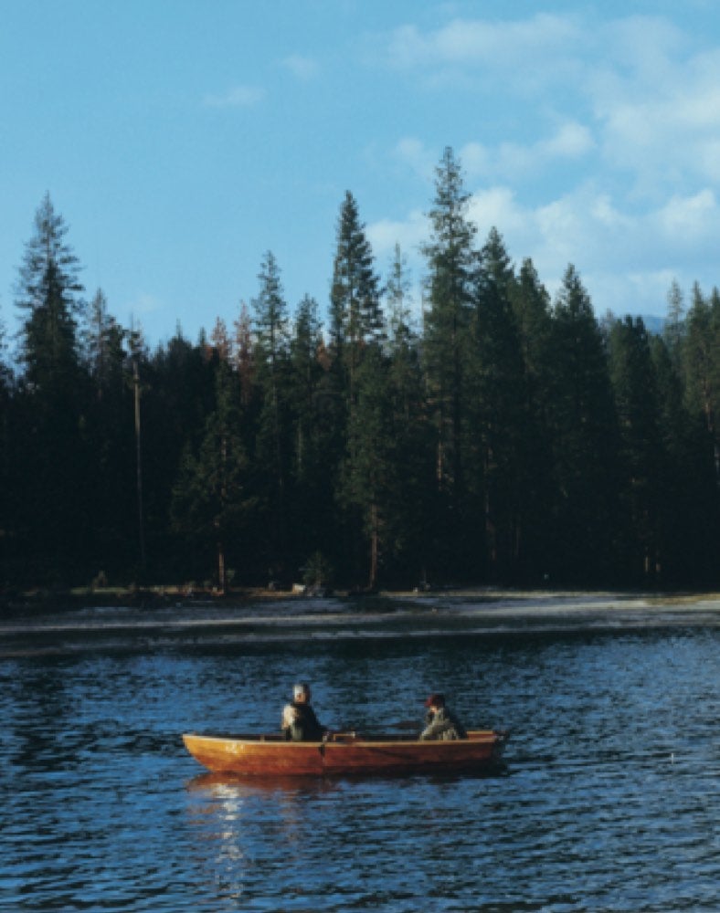 Red canoe in tree - lined lake